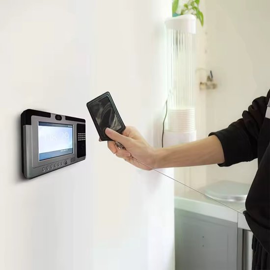 Une main tient un porte-carte noir avec cordon rétractable, tenu près d'un panneau d'accès mural.