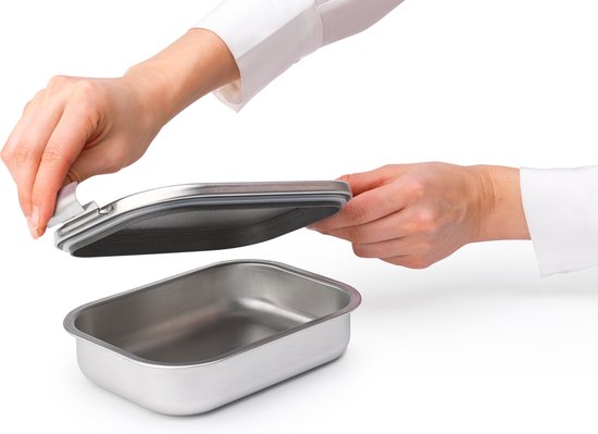 Mains d'une personne plaçant le couvercle en inox avec joint en silicone sur la boîte à lunch.