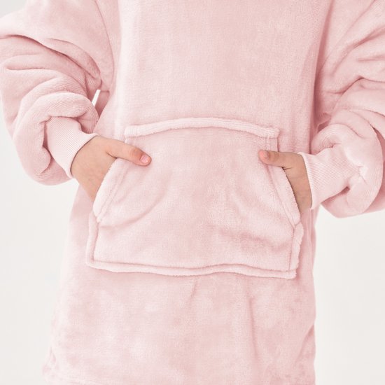 Close-up van de roze, oversized hoodie met capuchon, met de handen in de buidelzak.