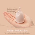 Une coupe menstruelle rose avec une 'encoche unique pour le doigt' dans une main, avec un e-book gratuit de conseils.
