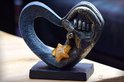 Zwarte hartvormige urn met gouden handen, met een amberkleurige glazen ster.