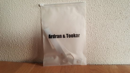 Transparante plastic verpakking met 'Ardran & Tookar' logo op een witte gestructureerde muur.