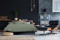 Groen satijnen dekbedovertrek met verticale strepen op een bed in een donkere slaapkamer.