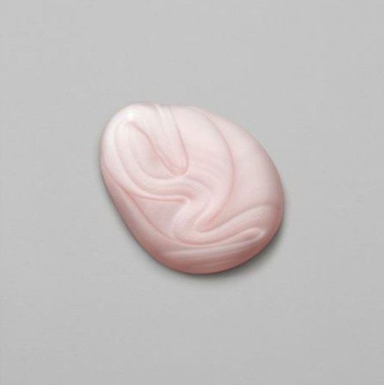 Een druppel lichtroze shampoo met witte spiraalvormige strepen op een grijze achtergrond.