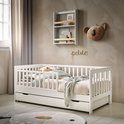 Wit kinderbed met uittrekbare lades, opgemaakt met beddengoed en een wanddecoratie van een koala hoofd.