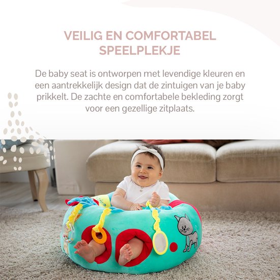 Baby met witte hoofdband zit vrolijk in een mintgroen zitje met kattenprint.