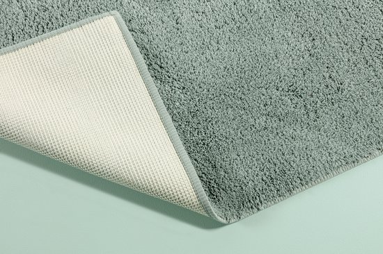 Een opgevouwen lichtgroene badmat met antislip onderkant.