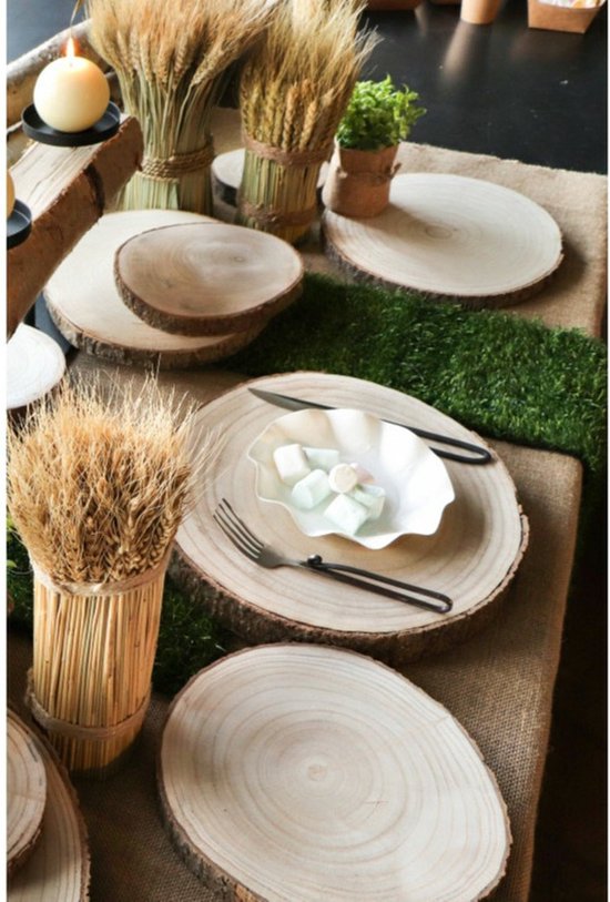 Houten boomschijf met gedroogde tarwestengels, kaars en kunstgras.