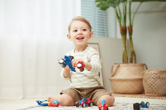 Jongen houdt een rood en blauw vliegtuigje met gele propeller vast.