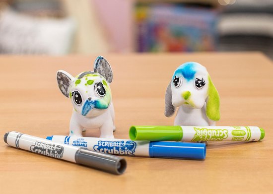 Twee Washimals dieren met groene en blauwe vlekken, liggend op een houten tafel met kleurpotloden.