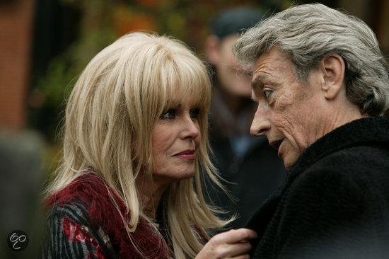 Close-up van een blonde vrouw en een oudere man die elkaar aankijken.