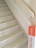 Witte trap met beschadigde treden en witte leuning, oranje doos.