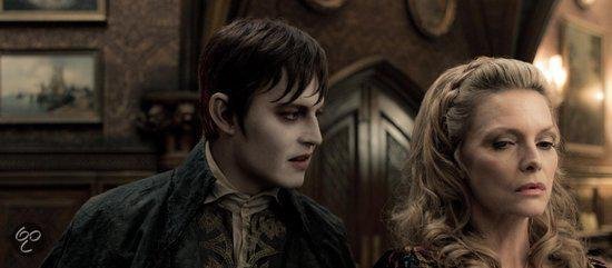 Barnabas Collins met bleke huid, donkere kledij, kijkt naar vrouw met blonde haren en donkerblauwe kledij.