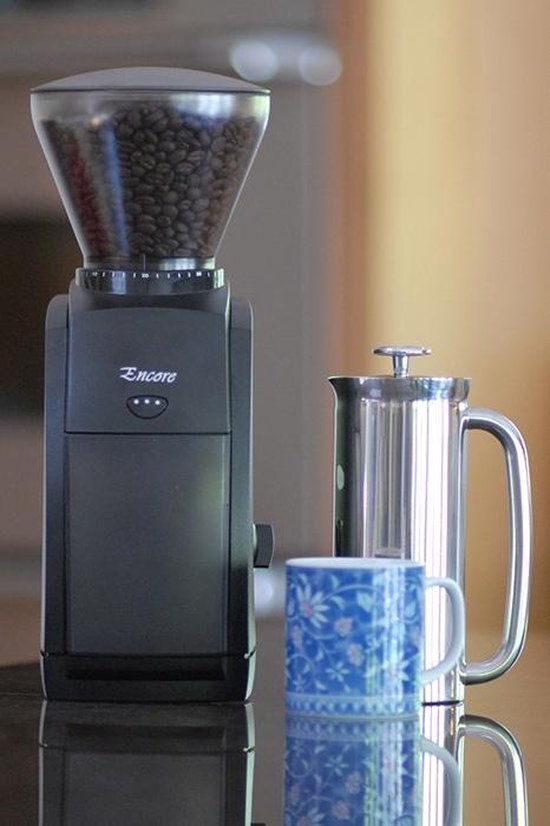 Zwarte elektrische koffiemolen 'Encore' van Baratza, naast een koffiezetapparaat en een mok.