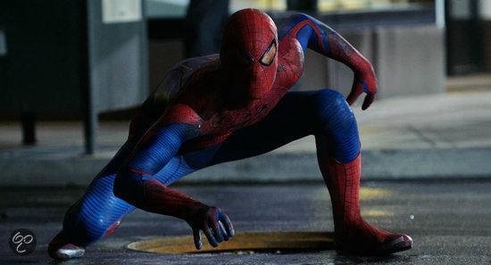 Spiderman in rood en blauw pak gehurkt op straat, met reflecties in zijn ogen.