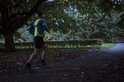 Man joggend in het donker met een fluoriserend geel hesje over een blauw shirt.