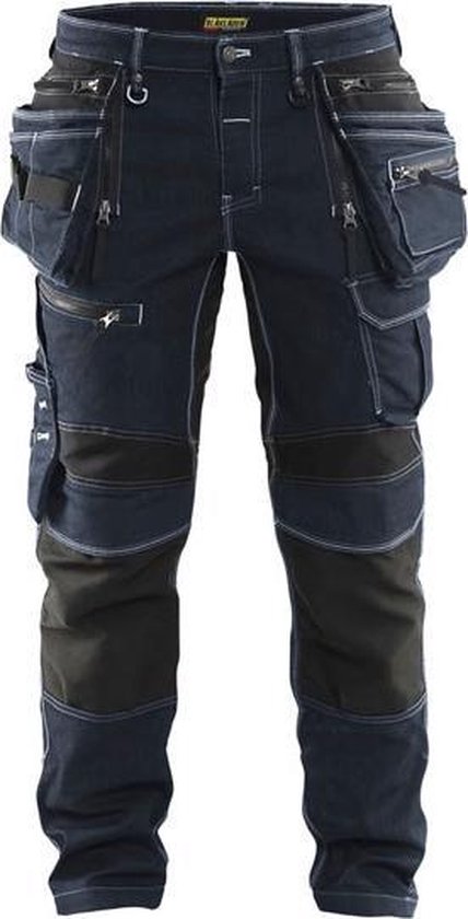 Donkerblauwe spijker werkbroek met zwarte knie- en scheenbeenpanelen, veel zakken, voorkant zichtbaar.