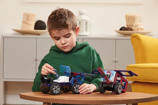 Jonge jongen speelt met Magformers-voertuigen aan een tafel, inclusief politie- en brandweerfiguren.