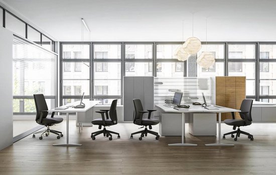 Moderne kantoorruimte met vier zwarte ergonomische bureaustoelen rond witte bureaus.