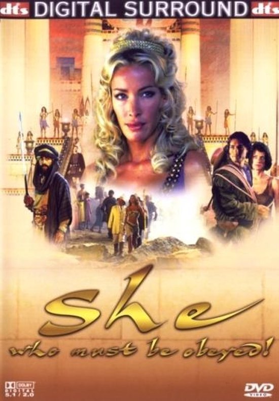 Poster van de film 'She' met een blondine met kroon, omringd door figuren en de tekst 'She who must be obeyed!'.