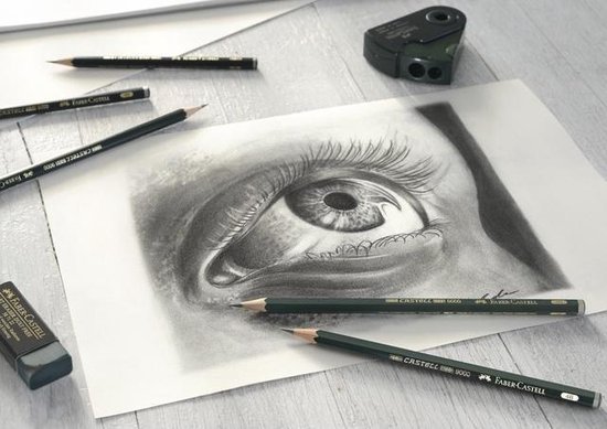Crayons et une gomme sur un croquis d'œil, avec un taille-crayon à l'arrière-plan.