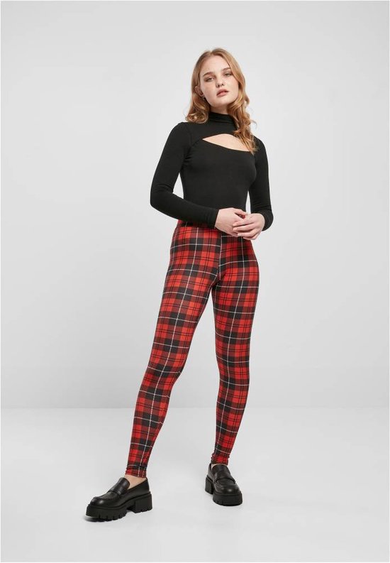 Model draagt een zwarte coltrui met uitsnijding en een rode ruit legging.