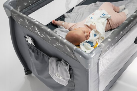 Close-up van een baby die in de grijze Lionelo Stefi Plus reiswieg met opbergzakjes ligt.
