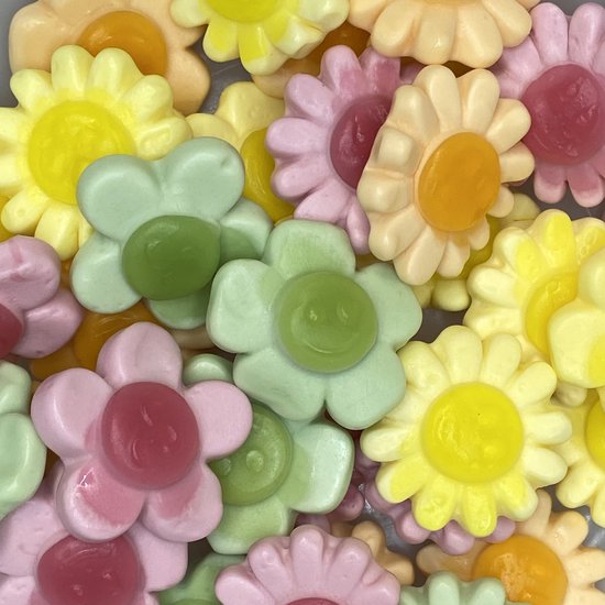 Veel kleurrijke snoepjes in de vorm van bloemen in pastelkleuren zoals roze, geel, groen en lila.