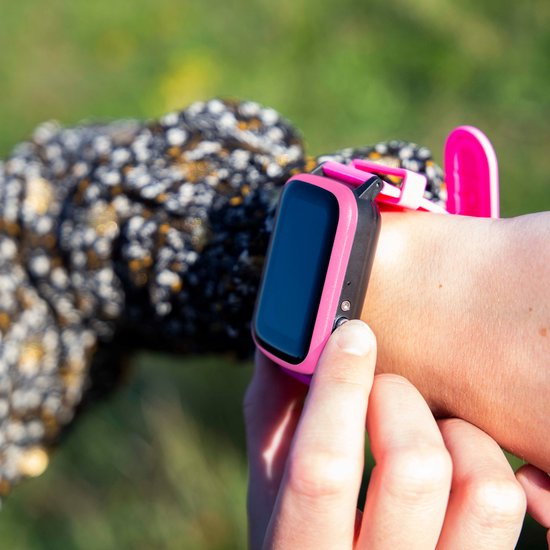 Roze one2track smartwatch om de pols van een kind, met de vinger op een knop.
