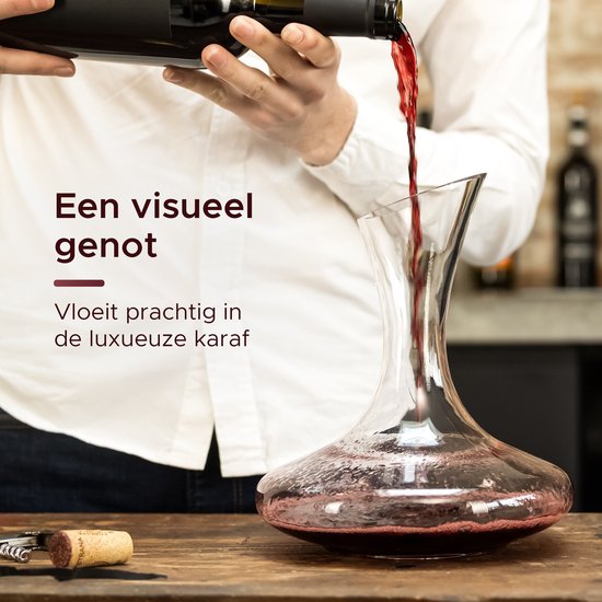 Du vin rouge est versé dans une carafe en verre à partir d'une bouteille.