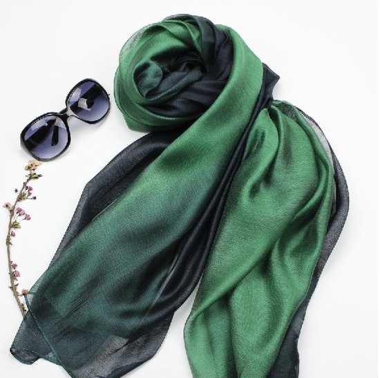 Donkergroene en smaragdgroene zijde blend sjaal, gepresenteerd met zonnebril en takje.