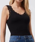 Model in zwart hemd met kanten rand, gedragen met blauwe jeans.