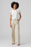 Femme portant un haut blanc court à volants et détails ajourés, et un pantalon cargo beige.