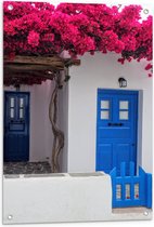 Tuinposter – Blauwe Deur met Roze Bloemen met Wit Huisje - 60x90 cm Foto op Tuinposter (wanddecoratie voor buiten en binnen)