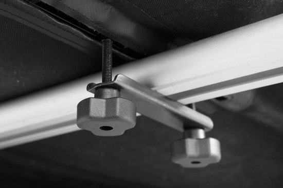Gedetailleerde foto van een metalen klem met twee knoppen voor het vastzetten van een dakkoffer.