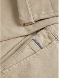Detail van de crèmekleurige chino broek, textuur en steekzak.