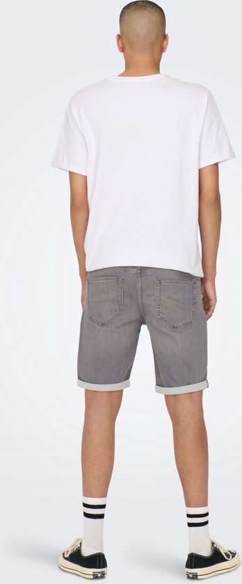 Man met grijze denim short met omgerolde zoom, witte t-shirt en gestreepte sokken.