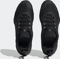 De bovenkanten van twee zwarte dames wandelschoenen met veters en zwarte Adidas-strepen.
