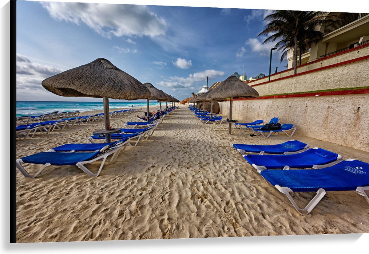 Canvas - Blauwe Ligbedden op Strand met Rieten Parasols - 120x80 cm Foto op Canvas Schilderij (Wanddecoratie op Canvas)