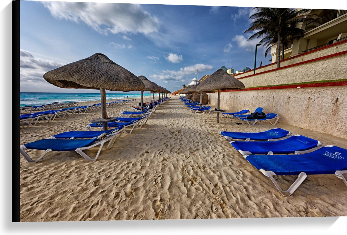 Canvas - Blauwe Ligbedden op Strand met Rieten Parasols - 90x60 cm Foto op Canvas Schilderij (Wanddecoratie op Canvas)