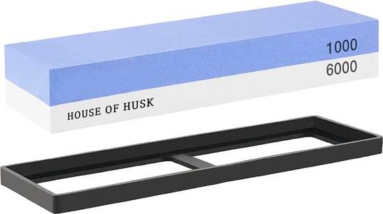 Een blauw-witte slijpsteen met 1000 en 6000 grit en een zwarte houder, merk 'House of Husk'.