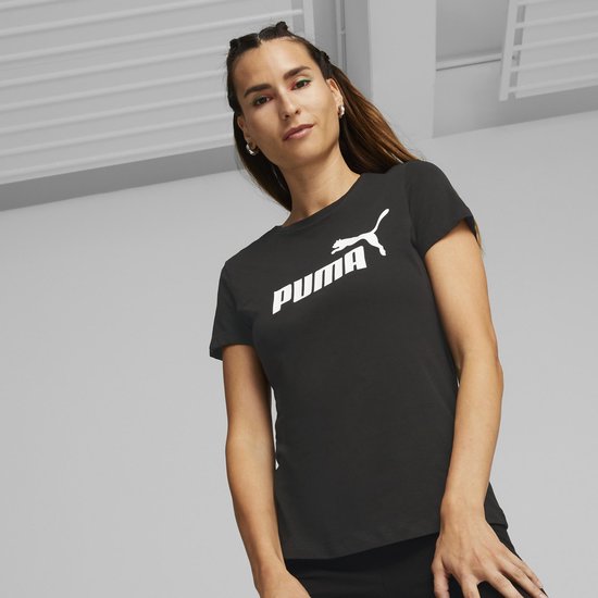 Vrouw met gestyled haar draagt zwart Puma T-shirt met wit Puma logo op de borst.