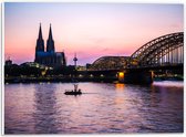 PVC Schuimplaat - Uitzicht op de Dom en Brug van Keulen tijdens de Avondzon in Duitsland - 40x30 cm Foto op PVC Schuimplaat (Met Ophangsysteem)