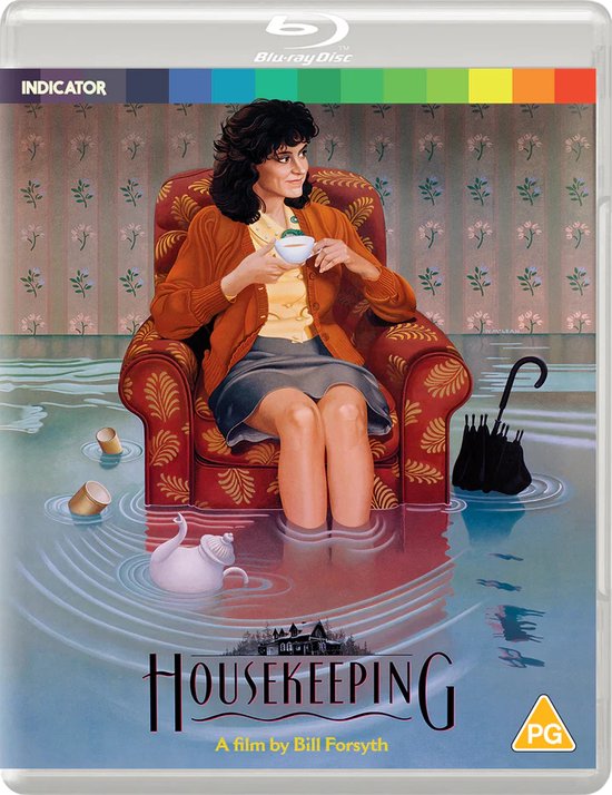 Een vrouw in een oranje vest en grijze rok zit in een stoel, omringd door water. De titel 'HOUSEKEEPING' staat onderaan.