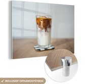 MuchoWow® Glasschilderij 90x60 cm - Schilderij acrylglas - Een kop ijskoffie op een houten tafel - Foto op glas - Schilderijen