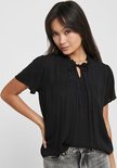 Zwarte blouse met korte mouwen, ruchekraag en strikdetail bij de hals. De stof heeft een subtiel stipjespatroon.