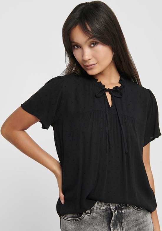 Zwarte blouse met korte mouwen, ruchekraag en strikdetail bij de hals. De stof heeft een subtiel stipjespatroon.