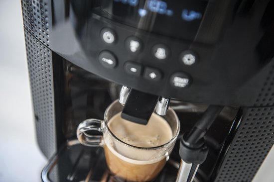 Close-up van een glas espresso dat wordt gezet in een zwarte Krups espressomachine.