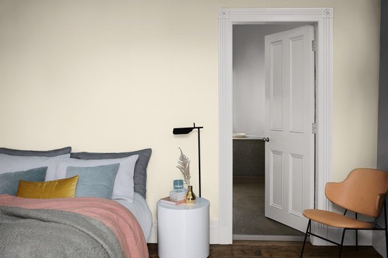 Slaapkamer met gestyled bed, nachtkastje en een open deur naar een badkamer.