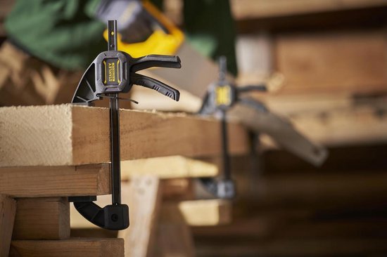 Twee zwarte Stanley Fatmax lijmklemmen op hout.